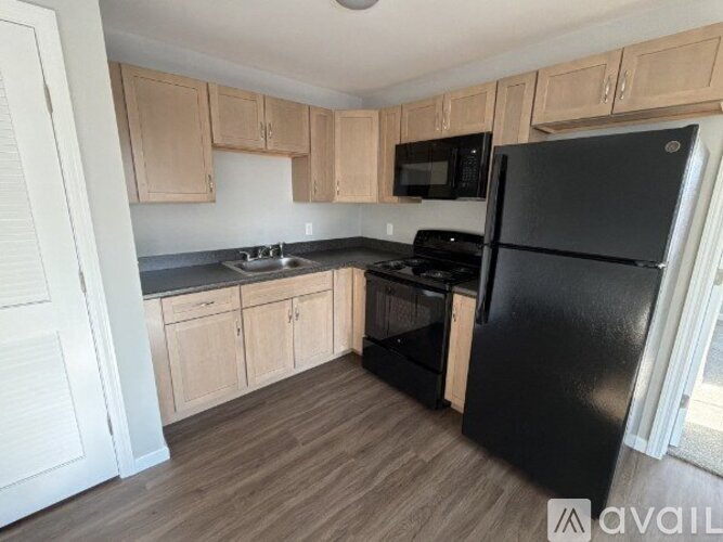 A kitchen with wooden cabinets and black appliances.