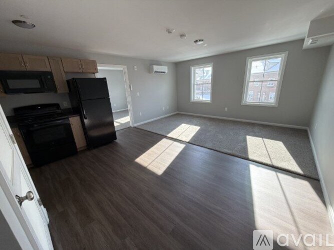 A kitchen with black appliances and wooden floors.