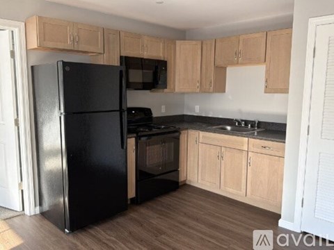 A kitchen with a black fridge and wooden cabinets.