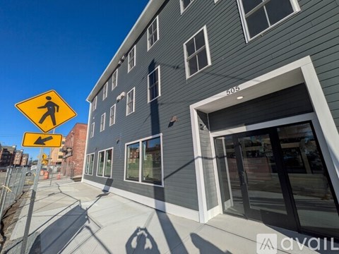 A pedestrian crossing sign is displayed in front of a grey building.