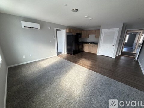 A spacious living room with a kitchen in the background.