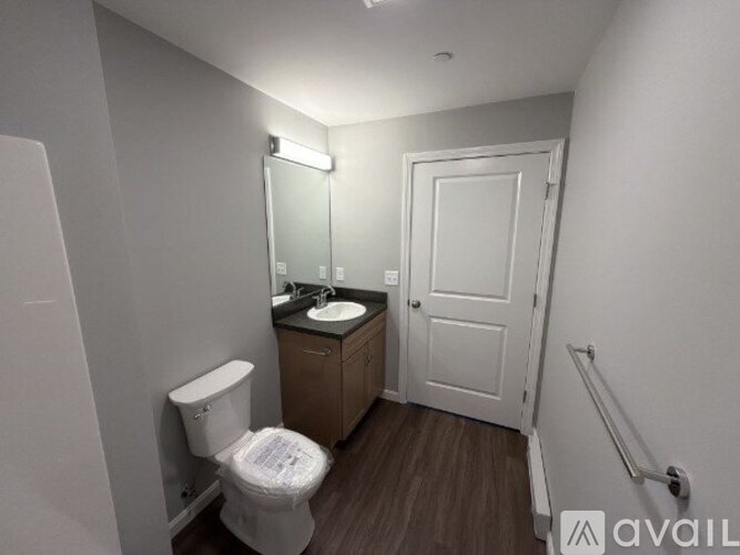 A small bathroom with a toilet, sink, and mirror.