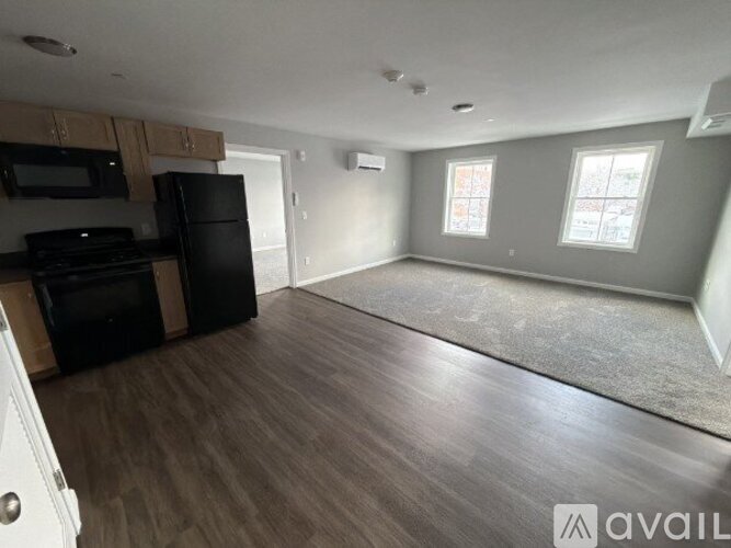 A spacious kitchen with black appliances and wooden flooring.