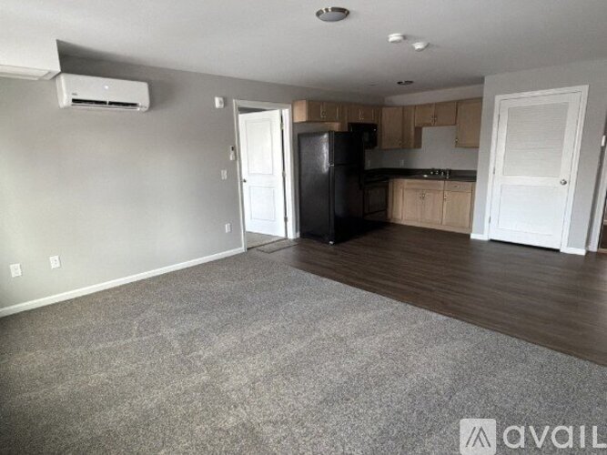 A spacious kitchen with a black refrigerator and white cabinets.