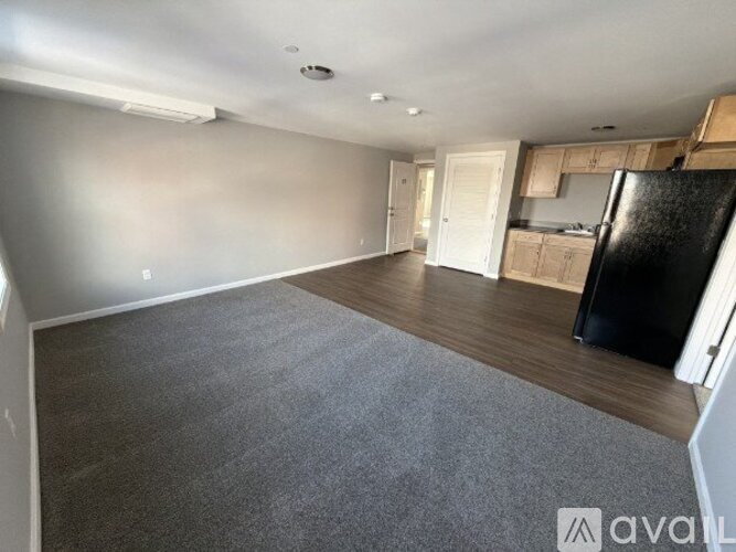 A spacious room with a black fridge and wooden cabinets.