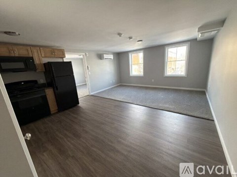 A spacious room with wooden flooring and a large window.