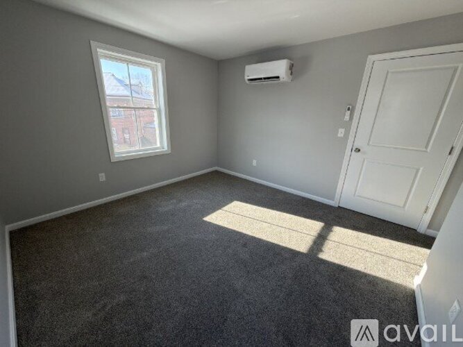 A room with a window, carpet, and a door.
