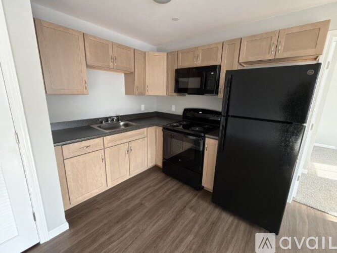 A kitchen with black appliances and wooden cabinets.