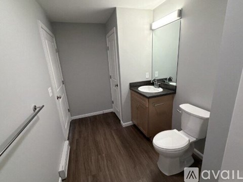 A bathroom with a toilet, sink, and mirror.