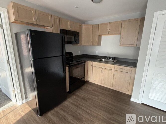 A black refrigerator in a kitchen with wooden cabinets.