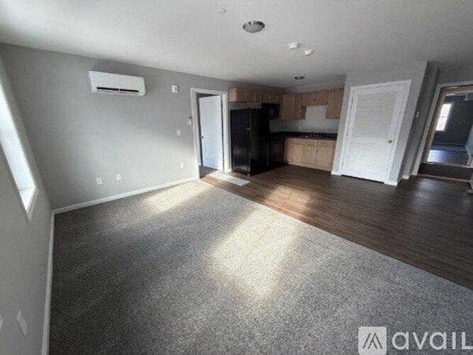 A spacious living room with a kitchen in the background.