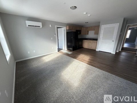 A spacious living room with a kitchen in the background.