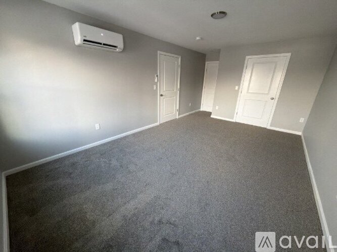 A room with grey carpet and three white doors.