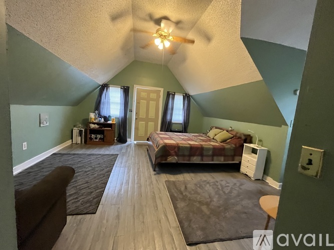 A bedroom with a bed, dresser, and ceiling fan.