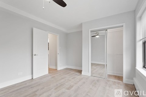 A spacious room with a ceiling fan and a door leading to another room.