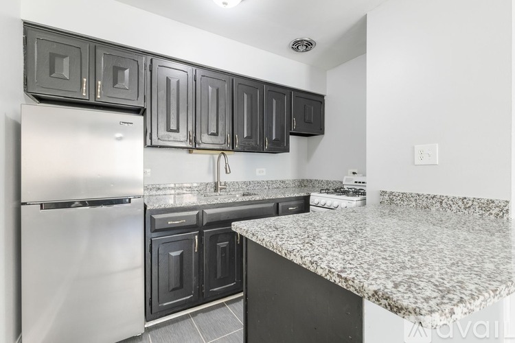 A kitchen with a white refrigerator and black cabinets.