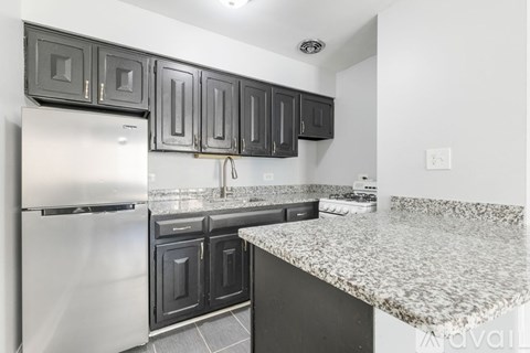 A kitchen with a white refrigerator and black cabinets.
