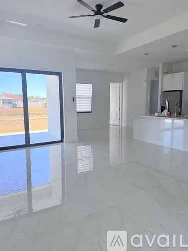 A spacious, empty room with a ceiling fan and large windows.