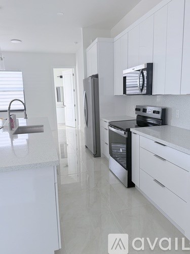 A modern kitchen with white cabinets and appliances.
