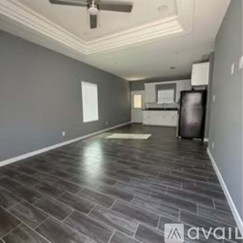 A spacious room with a ceiling fan and grey stone flooring.