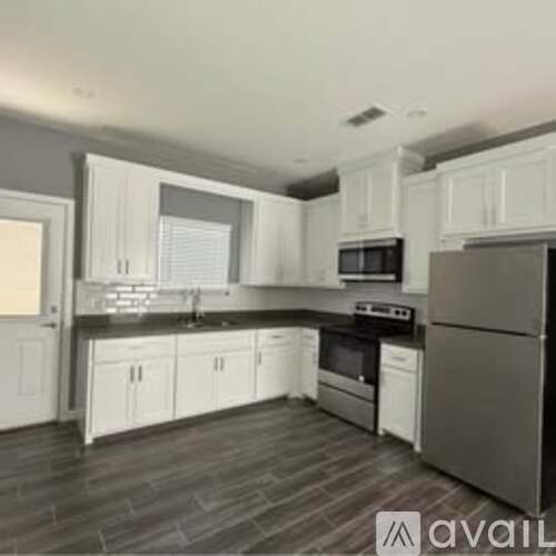 A kitchen with white cabinets and a black refrigerator.