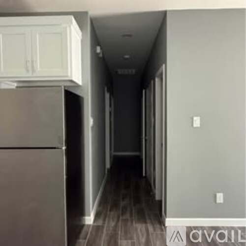 A long hallway with a refrigerator on the left.