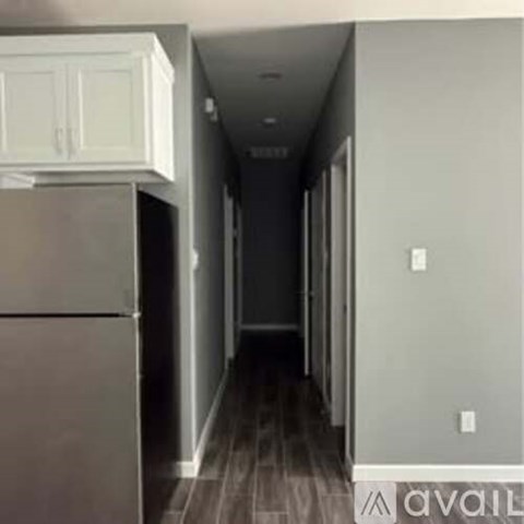 A long hallway with a refrigerator on the left.