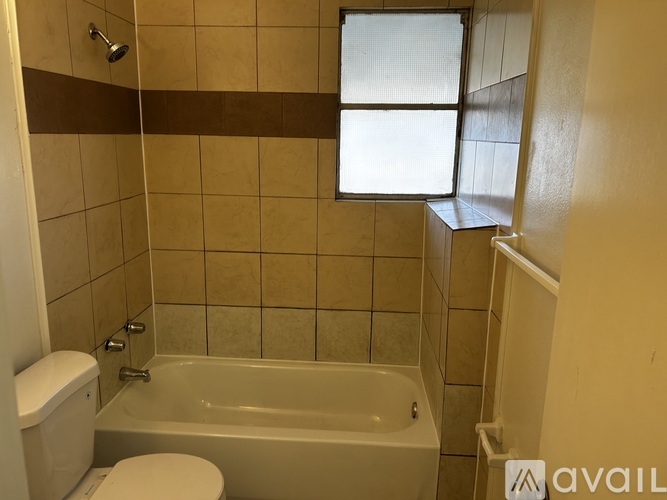 A bathroom with a toilet, tub, and window.
