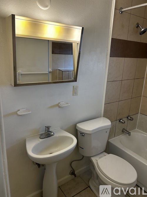 A bathroom with a toilet, sink, and mirror.