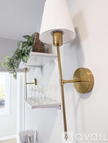 A white lamp with a gold base is on a wall.