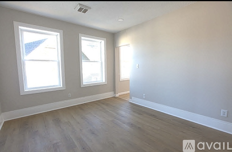 A room with two windows and wooden flooring is available for rent.