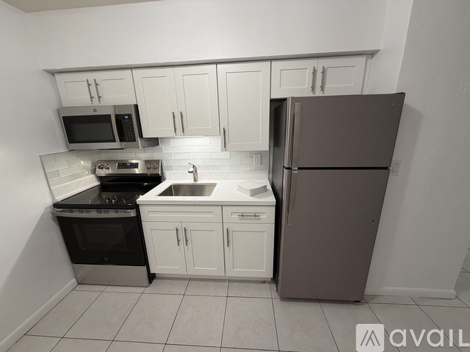 A kitchen with white cabinets and a brown refrigerator.