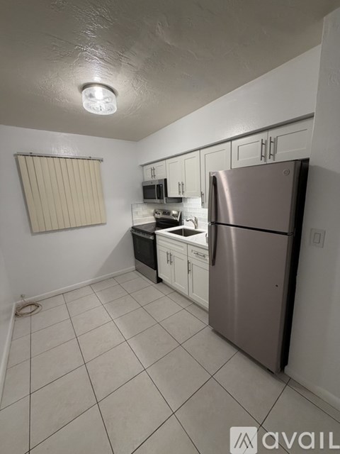 A kitchen with white cabinets and a stainless steel refrigerator.