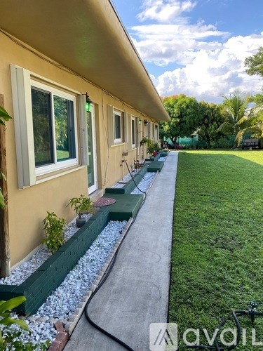A yellow house with a green border and a grey walkway.