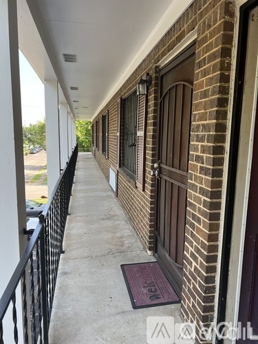 A balcony with a black railing and brown brick wall.