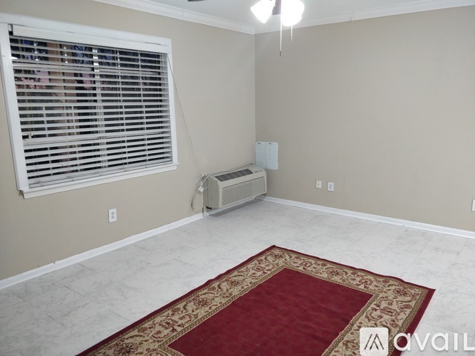 A room with a rug on the floor and a window with blinds.