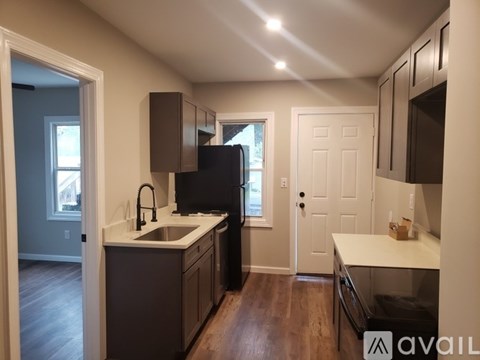 A kitchen with brown cabinets and a black refrigerator.