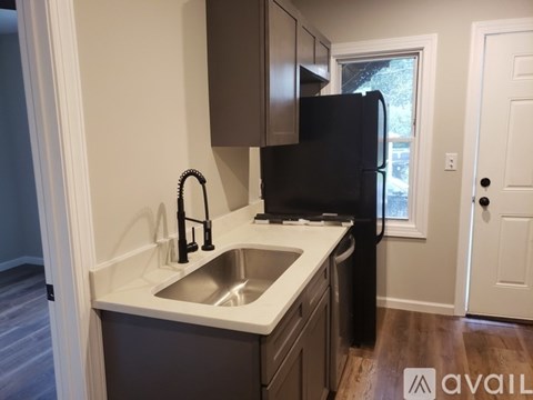 A kitchen with a black refrigerator and a white sink.