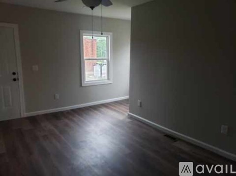 A room with a window and a wooden floor.