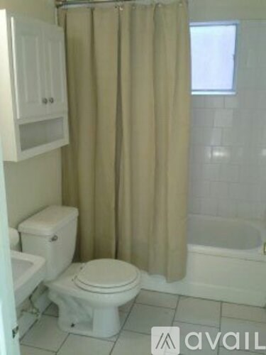 A white toilet sits next to a white bathtub in a bathroom.