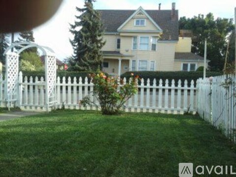 A white picket fence surrounds a green lawn.