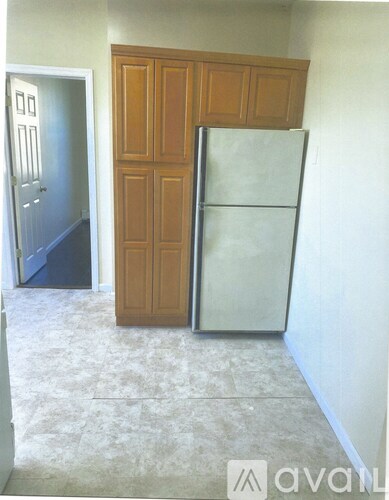 A kitchen with a white fridge and wooden cabinet.