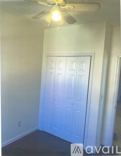 A room with a white door and a ceiling fan.