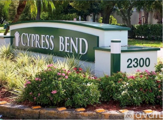 A sign that says Cypress Bend in front of some bushes.
