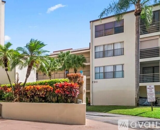 A building with the number 2311 on it is surrounded by palm trees and bushes.