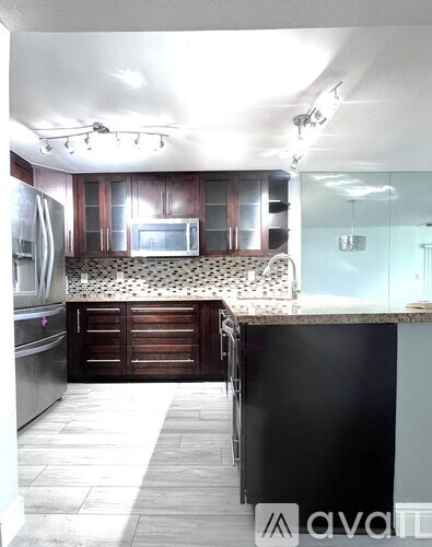 A kitchen with a black counter and a black and white tiled backsplash.