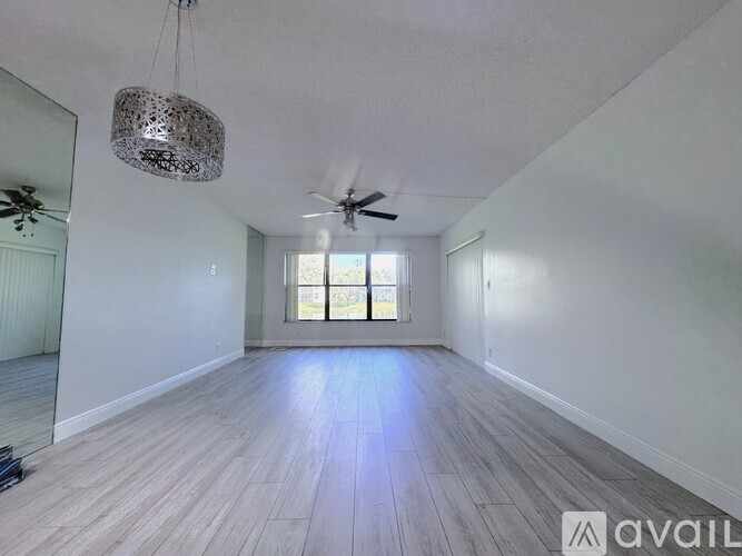 A spacious room with a ceiling fan and a large window.