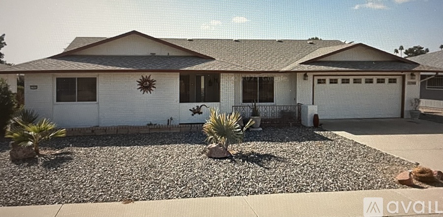 A white house with a gravel driveway and a palm tree in front.
