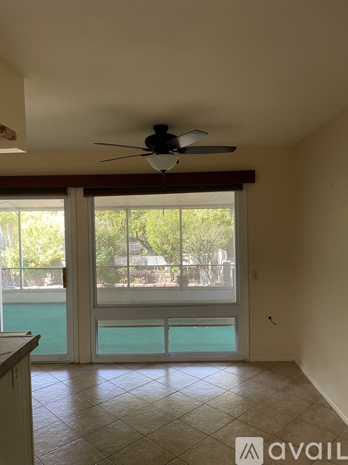 A room with a ceiling fan and sliding glass doors leading to a pool.