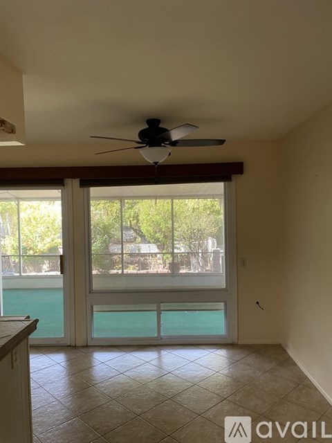 A room with a ceiling fan and sliding glass doors leading to a pool.